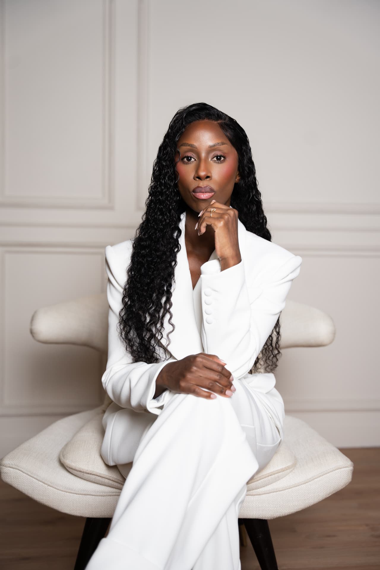 Nyambura Marincowitz, Rapid Transformational Therapy® practitioner and coach, seated in a white suit in a calm, softly lit room