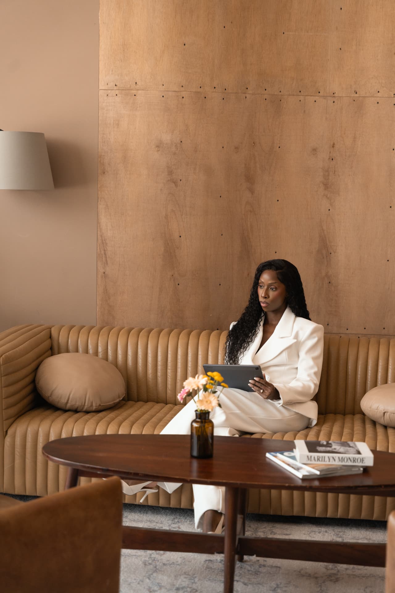 Nyambura Marincowitz seated on a tan leather couch with a tablet